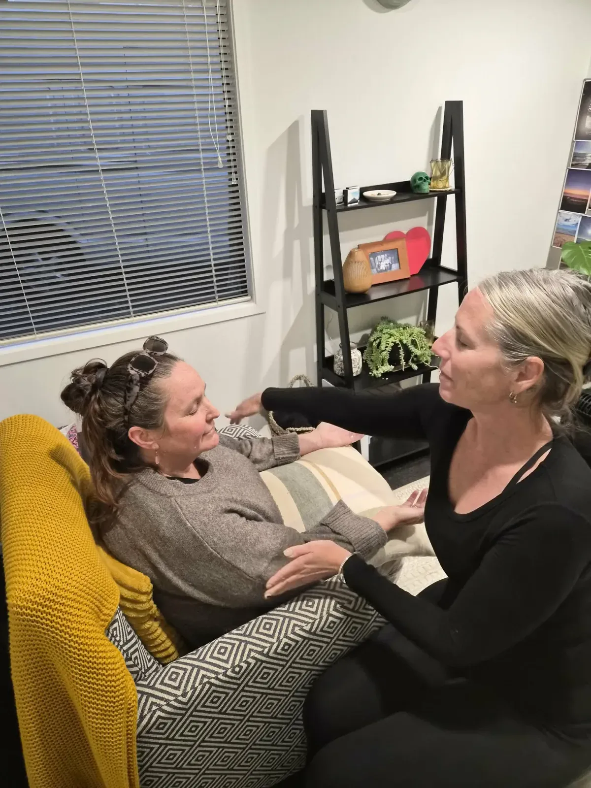 A session in progress: a client rests back in the armchair with her eyes closed while Lisa applies the light Havening touch along her arms.